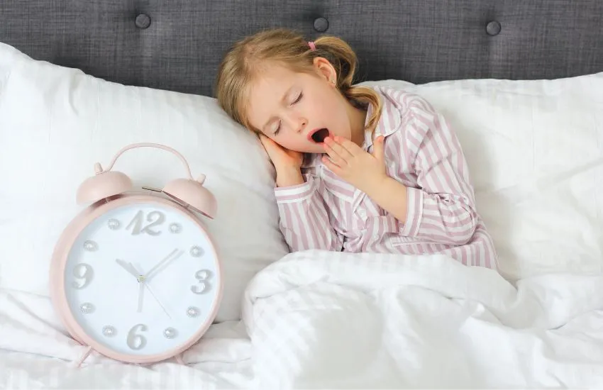 niña con una rutina de sueño en la cama después del verano